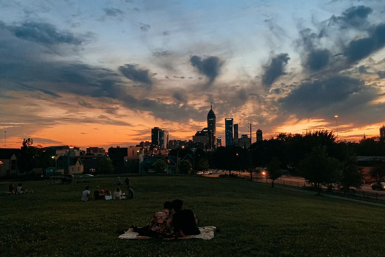 A couple on a hillside watching the Indianapolis skyline at sunset